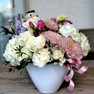 Surprise your loved ones with a beautiful flower arrangement featuring a soft teddy bear nestled among vibrant roses. This charming setup is perfect for birthdays, anniversaries, or just to say 'I care.'