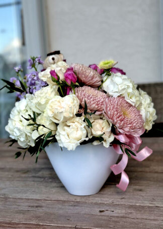 Surprise your loved ones with a beautiful flower arrangement featuring a soft teddy bear nestled among vibrant roses. This charming setup is perfect for birthdays, anniversaries, or just to say 'I care.'